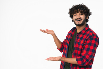 Cheerful young Hindi man in casual attire showing copy space isolated over white background. Handsome Indian boy pointing presenting free space for promotion goods offers