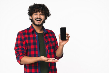 Smiley young Hindi man showing mobile phone screen for mockup isolated over white background....