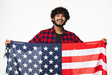 Indian young man holding American flag isolated over white background. Handsome Hindi boy in casual...