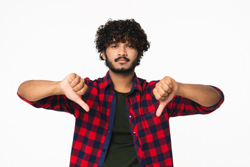 Sad young Hindi man showing thumbs down isolated over white background. Indian boy expressing...