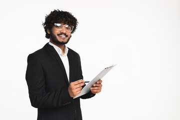 Handsome Indian businessman in black suit checking the quality with clipboard isolated over white...
