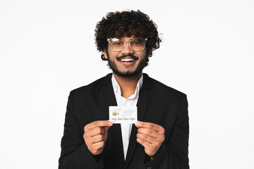 Cheerful young Hindu businessman holding credit card isolated over white background.