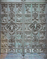 MILAN, ITALY - SEPTEMBER 16, 2024: The main bronze gate of the Cathedral with the new testament scenes by Ludovico Pogliaghi (1906).