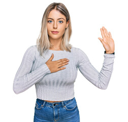 Beautiful blonde woman wearing casual clothes swearing with hand on chest and open palm, making a...