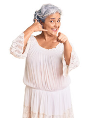 Senior woman with gray hair wearing bohemian style smiling doing talking on the telephone gesture...