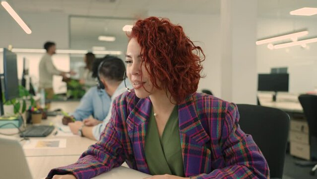 A friendly customer support operator is talking on headset with client.