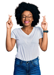 Young african american woman wearing casual white t shirt gesturing finger crossed smiling with...