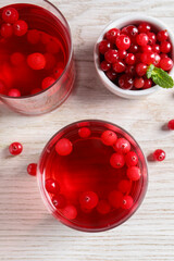 Tasty cranberry juice in glasses and fresh berries on white wooden table, flat lay