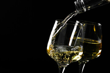 Pouring tasty aromatic wine in glass on black background, closeup. Space for text