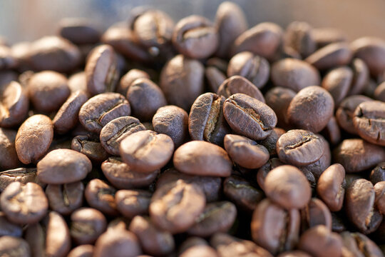 A close-up image capturing the rich, dark tones of carefully roasted Arabica coffee beans. Each bean glistens, highlighting the meticulous roasting process that enhances flavor and aroma