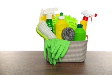 Different cleaning products in basket on wooden table against white background