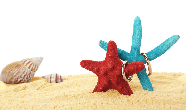 Honeymoon concept. Two golden rings, sea stars, seashells and sand isolated on white - Powered by Adobe