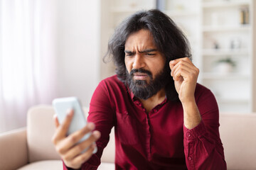 Man frustrated with smartphone at home, bad news - obrazy, fototapety, plakaty