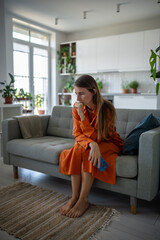 Stressed sad woman sits on couch reflecting deep in thought. Serious, melancholic, focused female...