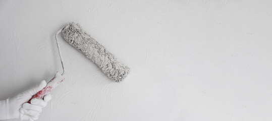 Painting the wall with a roller with white paint. Painting a bare wall with a roller with white...