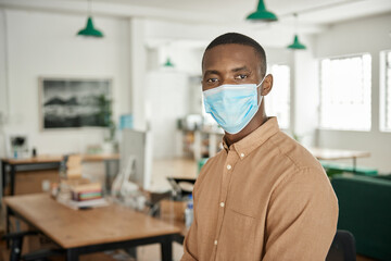 Fototapeta na wymiar Young African businessman wearing a protective face mask at the office