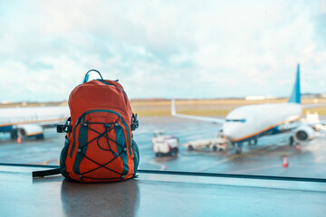 orange backpack in an airport on floor against planes. Travel touristic concept. travel light