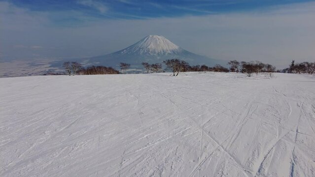 Niseko, Japan: Point of view of a snowboarder riding the slope in the famous Niseko ski resort in Hokkaido with Mt Yotei in the backround on a sunny winter day in northern Japan