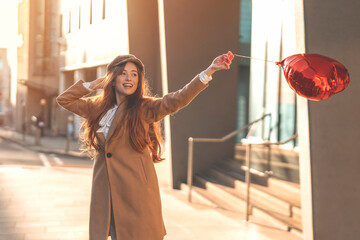 young happy woman with a heart-shaped balloon falling a love, having a fun day, walking around...
