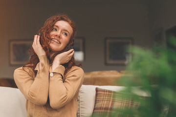 Happy young redhead woman in brown shirt  listening to favorite songs, audiobooks, podcasts on...