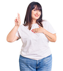 Young plus size woman wearing casual clothes smiling swearing with hand on chest and fingers up,...