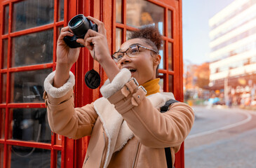 Amazing woman using camera against red  phonebox traveling around English city Enjoying travel...