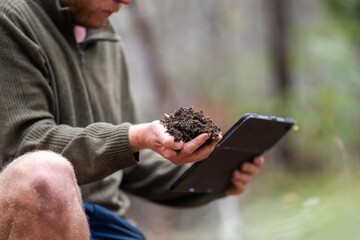 farmer collecting soil samples in a test tube in a field. Agronomist checking soil carbon and plant health on a farm © Phoebe