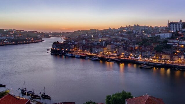 Panorama old city Porto at river Duoro, with Port transporting boats day to night transition timelapse with the Arrabida bridge after sunset, Oporto, Portugal