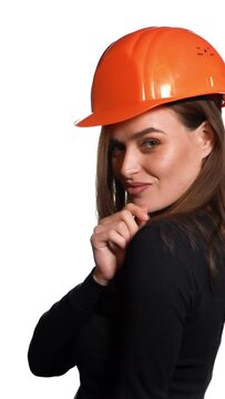 Beautiful woman in orange helmet and black golf is poses for the camera on a white background in the studio. Vertical video