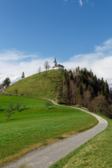 A church on the green hill under the blue sky on the cloudy day.