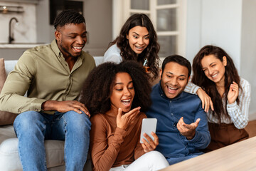 Obraz premium Group of friends laughing with smartphone at home