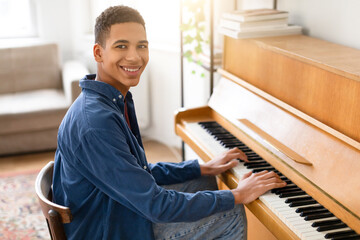Smiling black guy pianist enjoying music at home