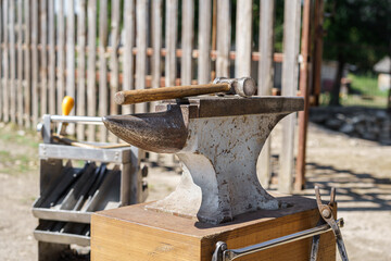 Close up of an anvil with hammer in a sunny day. Farrier tools in the background. Horseshoeing preparation is in progress