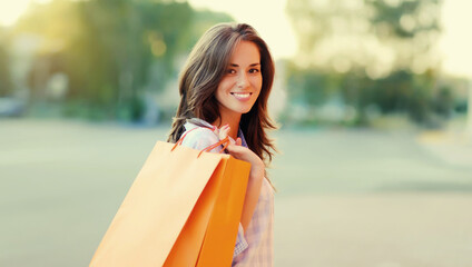 happy brunette young woman with shopping bags walking in the city