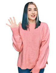 Young modern girl wearing pink wool winter sweater showing and pointing up with fingers number five while smiling confident and happy.