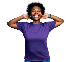 African american woman with afro hair wearing casual purple t shirt relaxing and stretching, arms...