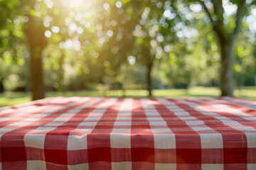 Close-up of red and white checkered picnic tablecloth with bokeh greenery in sunlit park - Powered by Adobe