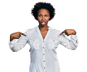 African american woman with afro hair pointing with fingers to herself in shock face, looking...