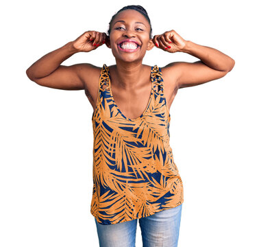 Young african american woman wearing casual clothes smiling pulling ears with fingers, funny gesture. audition problem