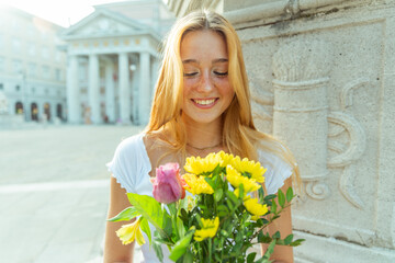 A happy girl looks at a bouquet of flowers she has just received as a gift, romantic gesture
