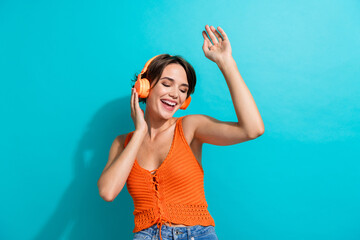 Photo of overjoyed lovely woman dressed knitwear singlet touching headphones hand up listen music...