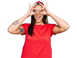Young hispanic woman wearing casual clothes doing ok gesture like binoculars sticking tongue out, eyes looking through fingers. crazy expression.