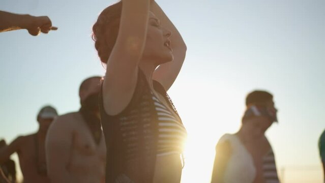 Diverse group of fans dancing at openair live rock concert. Asian woman jump at music festival outdoor. Rebellious young anarchist people listening to alternative punk songs. Crowd clapping at the gig