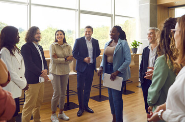 Group of business people chatting after meeting. Diverse company employees listening african...
