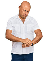 Mature middle east man with mustache wearing casual white shirt checking the time on wrist watch, relaxed and confident