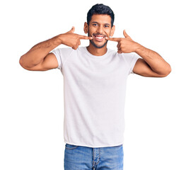Young latin man wearing casual clothes smiling cheerful showing and pointing with fingers teeth and...