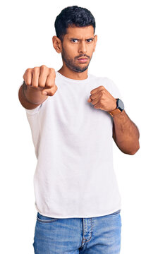 Young latin man wearing casual clothes punching fist to fight, aggressive and angry attack, threat and violence