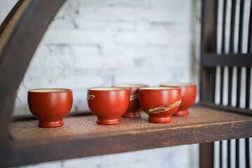 Set of clay crockery or ceramic kitchenware which are kept on the wooden shelf. Interior decoration object photo.