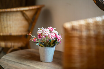 An artificial rose flower pot in placed on the wooden table for interior decoration. Close-up and selective focus.