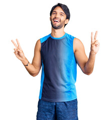 Handsome hispanic man wearing sportswear smiling looking to the camera showing fingers doing...